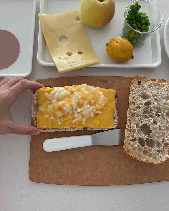 白と茶色のトーンのキッチン、まな板の上にパンとチーズが配置された雰囲気のあるインテリア