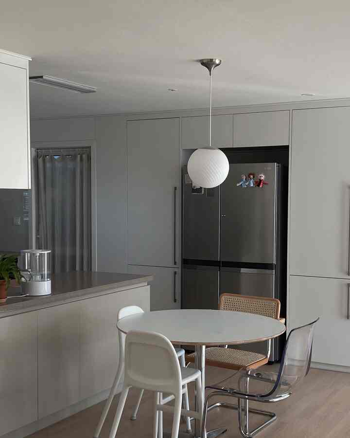 白とナチュラルな色調のダイニング、円形テーブルと様々な椅子が配置された雰囲気のある家族の食事スペース