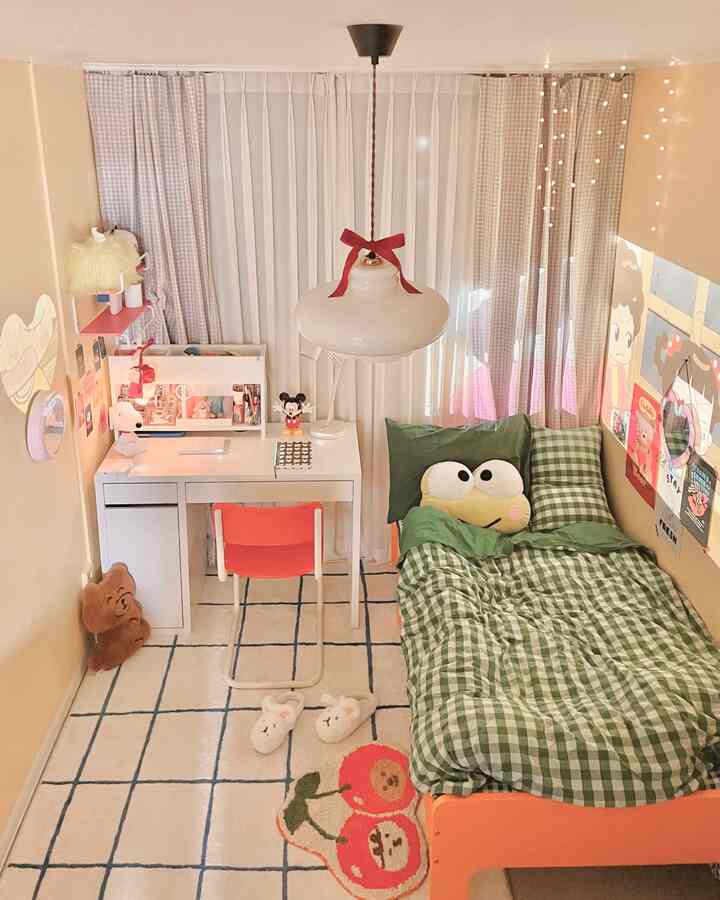 Warm beige-toned kids' room featuring an orange bed with green checkered bedding, white desk, and orange chair arranged cozily