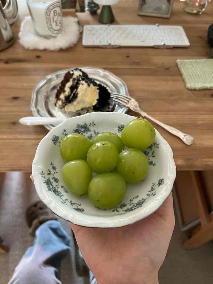 Cozy home cafe space featuring a warm wood tone multi-purpose table with candle, small mood lamp, dessert, and green grapes