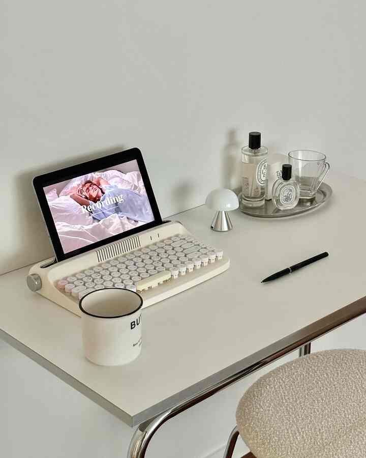 Modern white and silver toned home office space featuring a clean desk with digital device, mood lamp, and tray in a simple arrangement