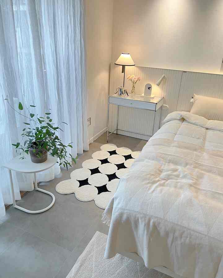 Bright white and beige bedroom featuring a bed, side tables, floor lamp, and cozy decor elements