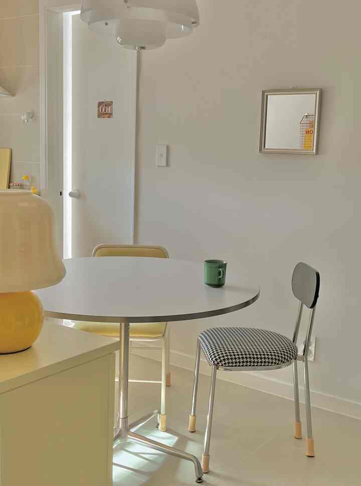 Bright white kitchen with yellow accents featuring a simple round table and dining chairs in a minimalistic setting