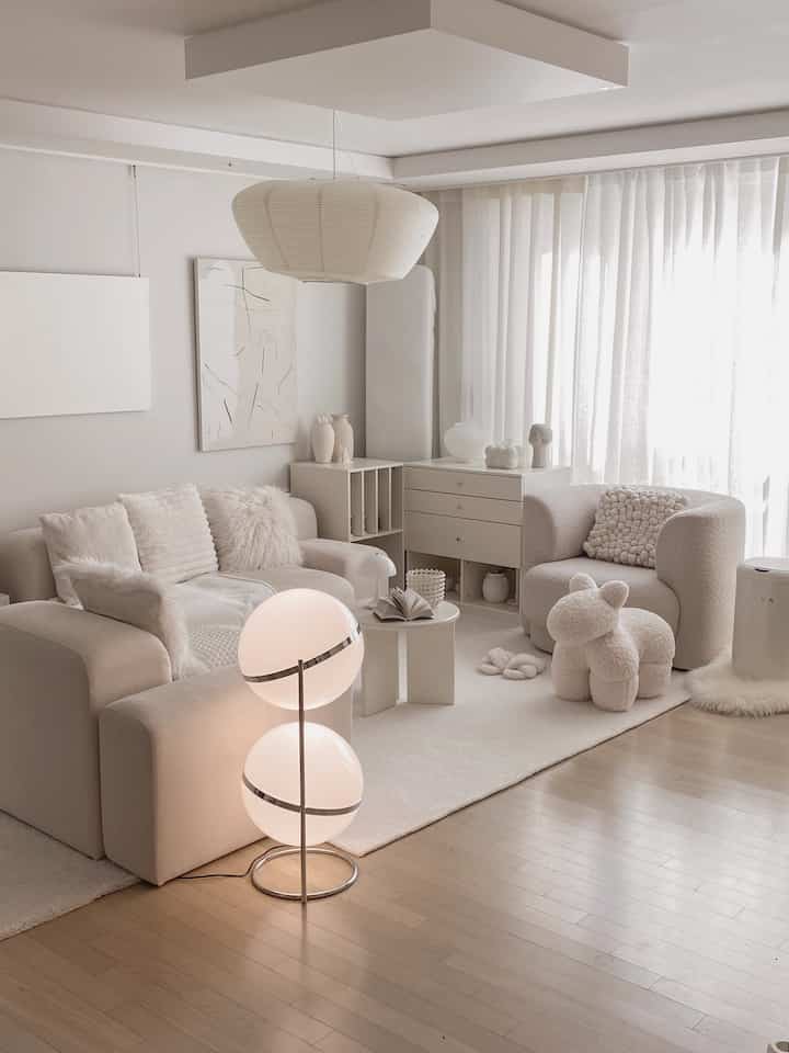 Natural modern living room in white and beige tones, featuring two sofas, a large rug, and a plush dog-shaped decor item