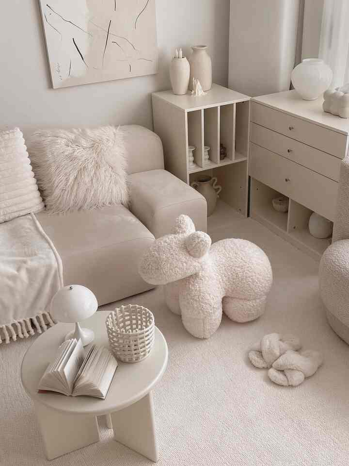 Calm ivory-toned living room featuring cream sofa, plush bear-shaped stool, and simple side table creating a cozy atmosphere