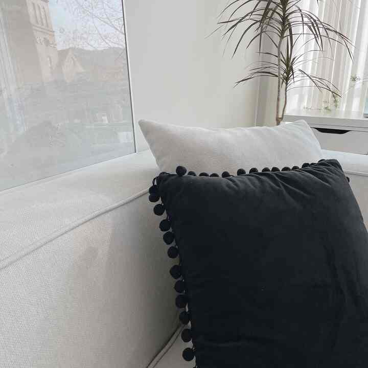 Monotone living room in white and black tones featuring white sofa with black pompom cushion and framed art for a simple interior