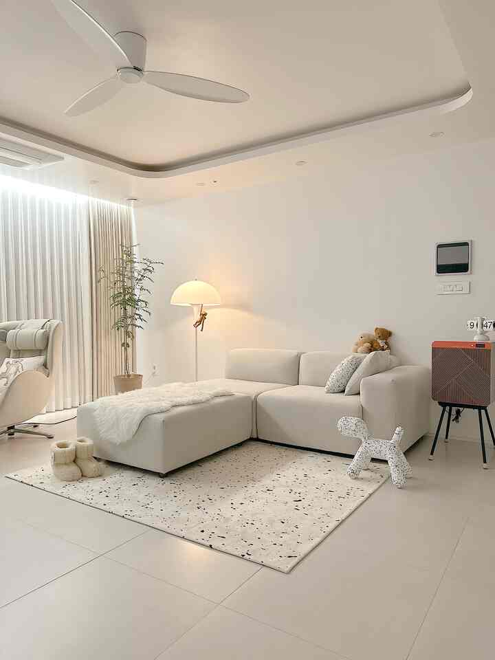 Bright ivory and white toned living room featuring modular sofa, rug, and floor lamp creating cozy ambiance