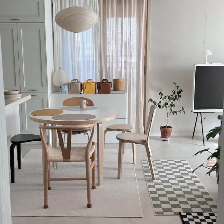 アイボリーとベージュの色調のリビングルーム、丸いダイニングテーブルと椅子が配置され、暖かく居心地の良い空間