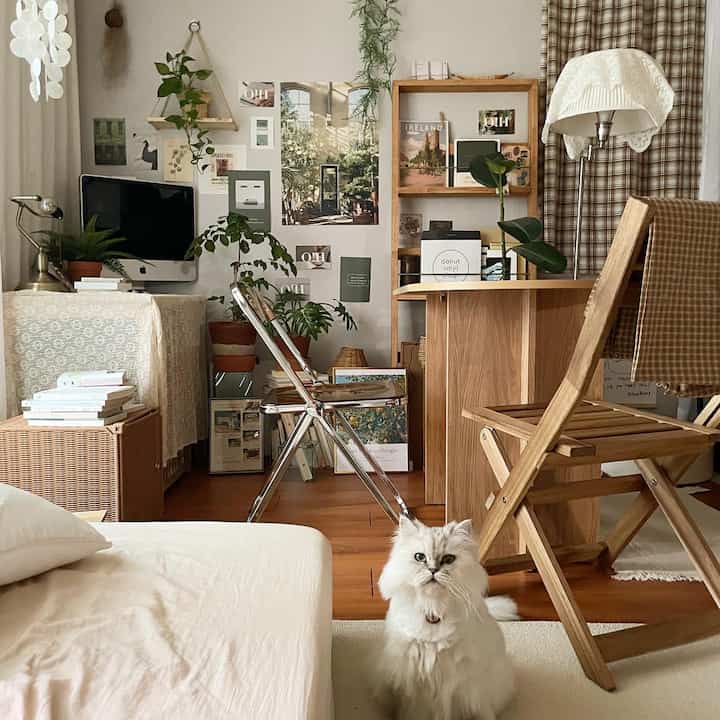 Wood tone and beige living room featuring desk, chairs, plants, and a white cat creating a cozy home office interior