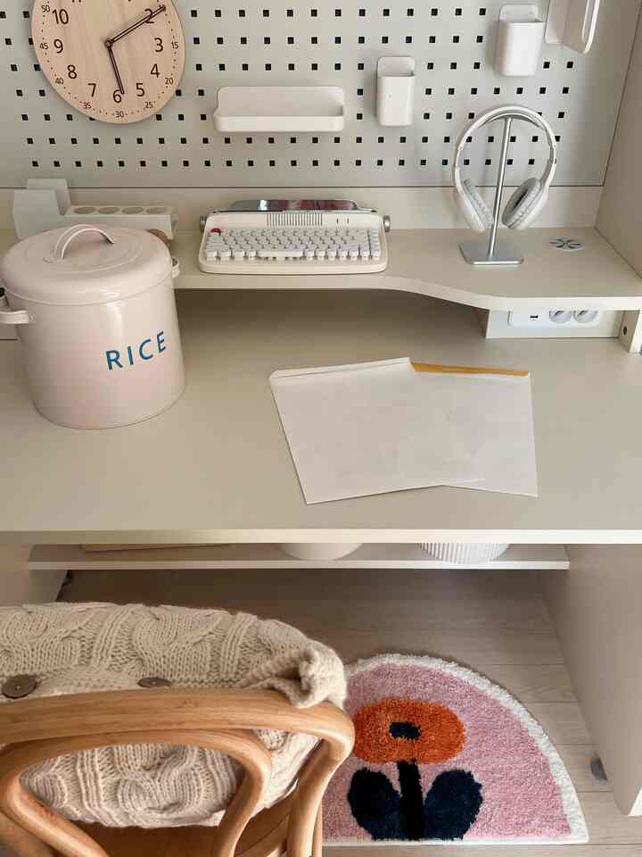 White and beige toned home office space featuring a desk with typewriter and headphones in a tidy workspace