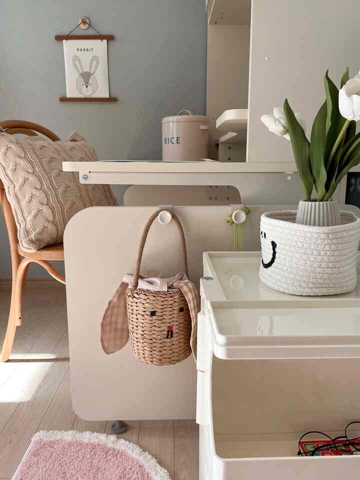 ベージュとナチュラルトーンのリビング、ラタンチェアとニットクッション、バスケットが配置された雰囲気のあるインテリア