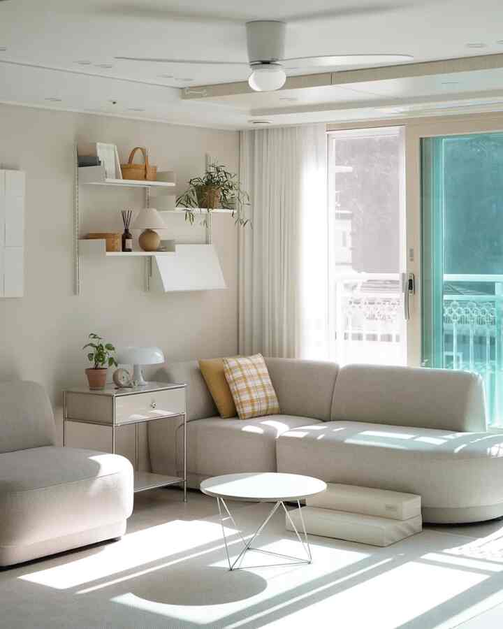 Bright white and beige toned living room with a corner sofa and shelves, creating a natural and harmonious atmosphere