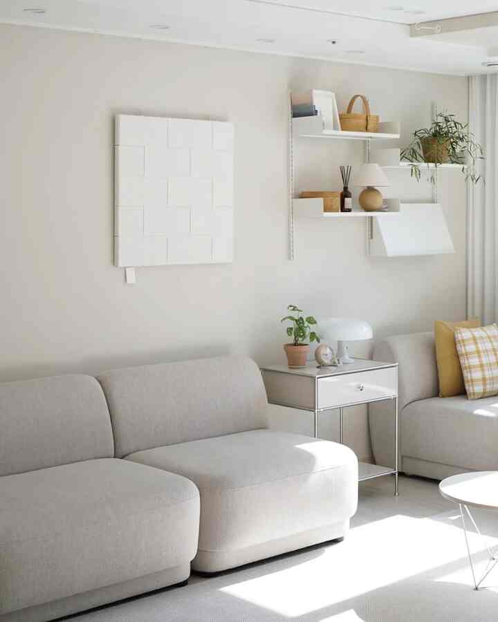 ベージュとホワイトの色調のリビング、モダンでナチュラルなソファと収納棚が整然と配置された雰囲気のあるインテリア