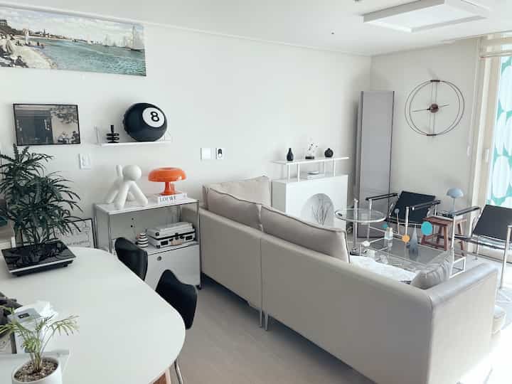 Bright white and beige toned living room featuring a beige sofa and glass coffee table in a clean, modern space