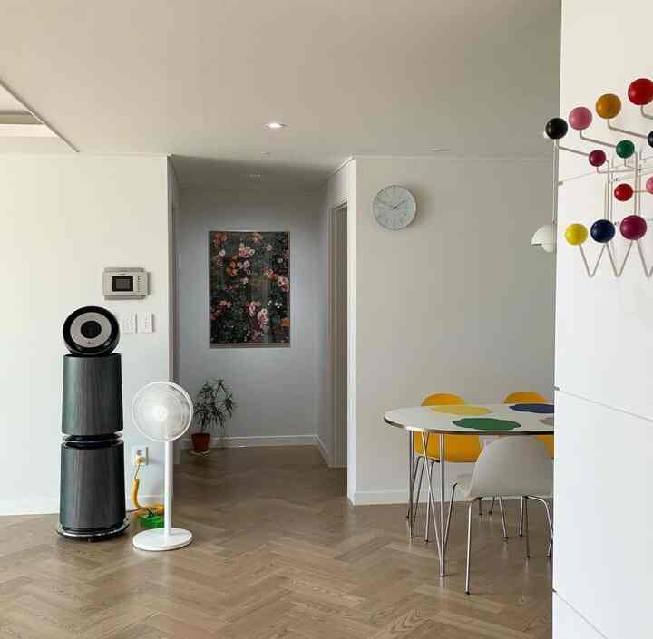 White-walled living and dining room with wood-tone parquet floor, minimal furniture and a wall clock in a simple modern style