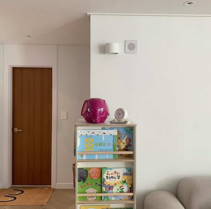 White and natural tone living room featuring a compact bookshelf with an elephant objet and a table clock in a simple atmosphere