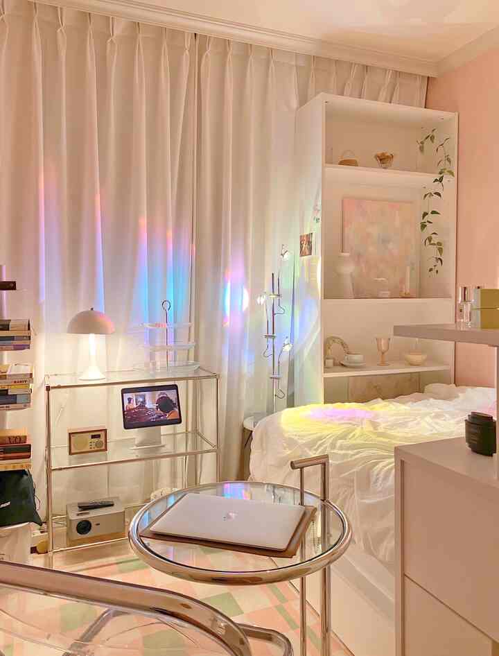 A cozy modern bedroom featuring white and pink tones, glass shelves, and curtains