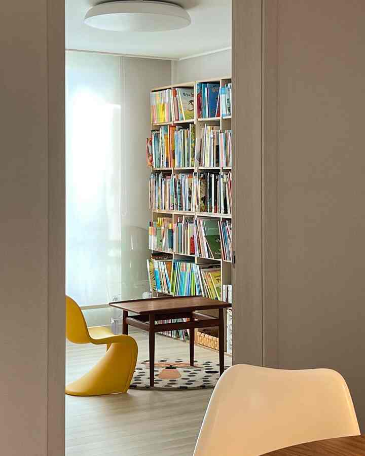 ホワイトとイエローの色調が調和する子供部屋の本棚とジュニアチェアが配置されたモダンでナチュラルな読書スペース