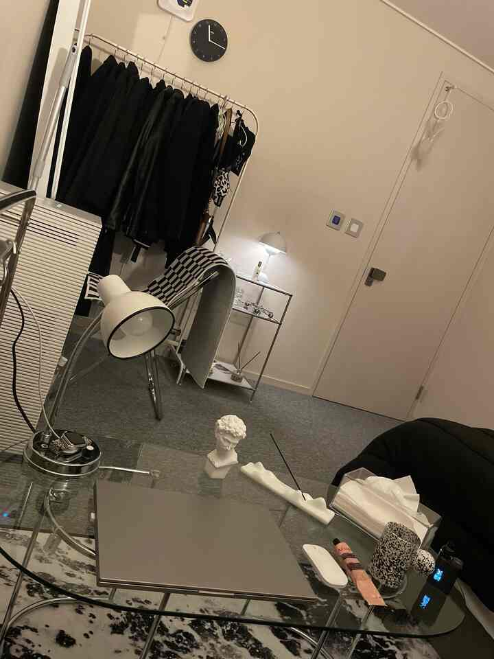 White and gray toned studio apartment home office featuring a glass table and coat rack with a clean modern interior
