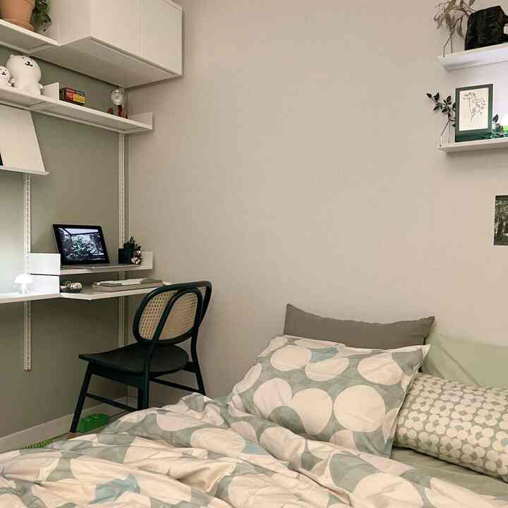 Beige and mint toned small room featuring wall shelves, compact desk, and cozy mattress in a natural modern style