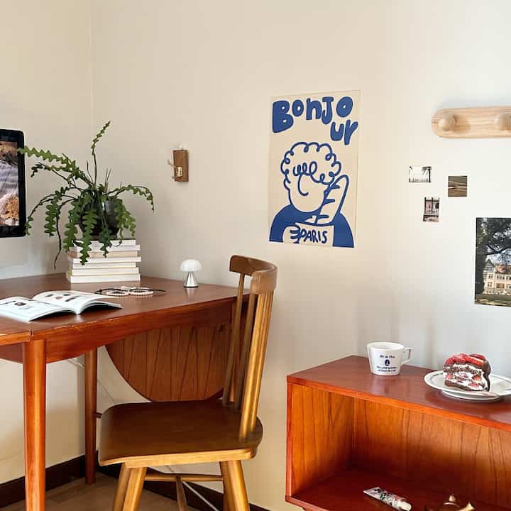 Warm natural wood-toned study space featuring a desk, chair, plant, and dessert arranged in a cozy interior