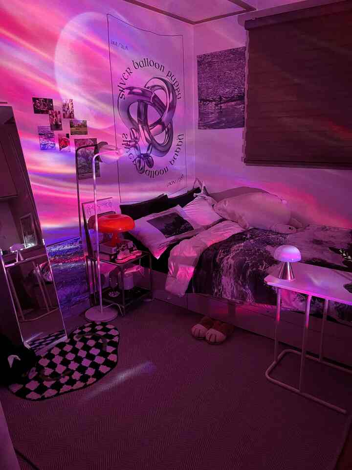 ピンク色の照明に包まれた小さな寝室、ベッドとムードランプ、姿見が配置された雰囲気のあるインテリア