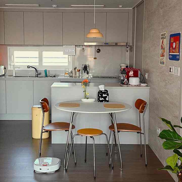 White and brown toned kitchen featuring a round dining table and chairs with a clean, modern atmosphere