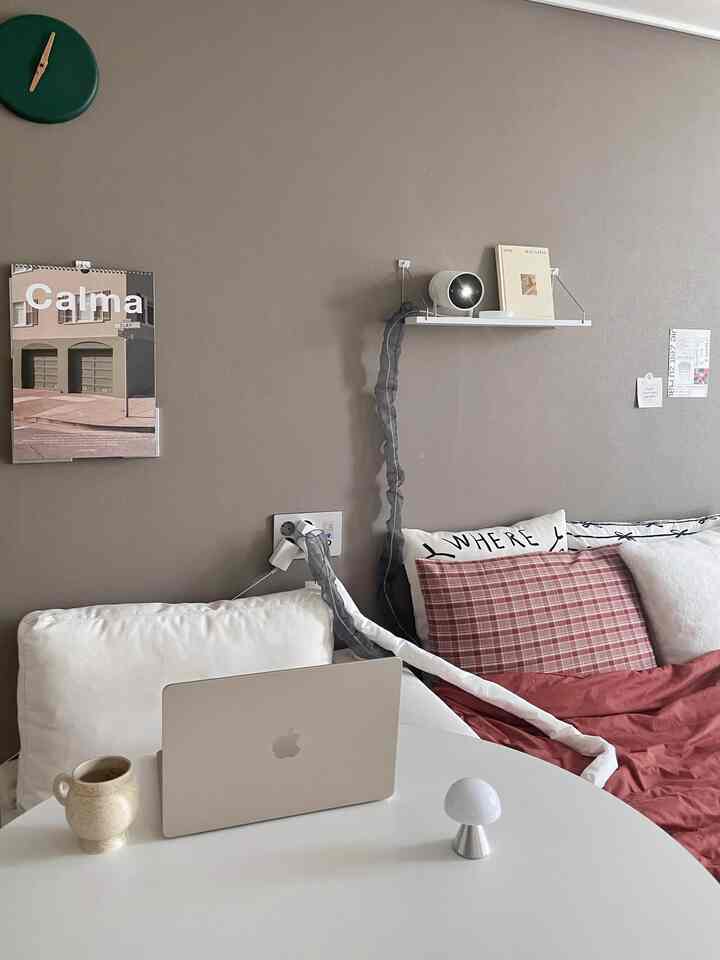 Beige-toned wall with white sofa, laptop and lamp on desk in a simple and cozy home office space