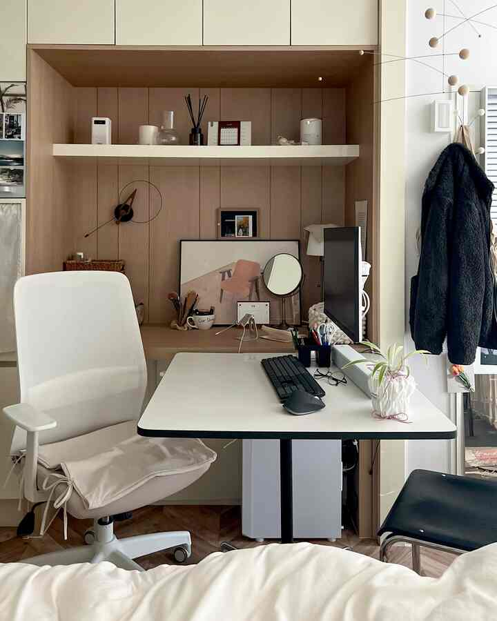 White and wood tone small home office featuring desk, office chair, monitor, and plant with a minimal natural atmosphere