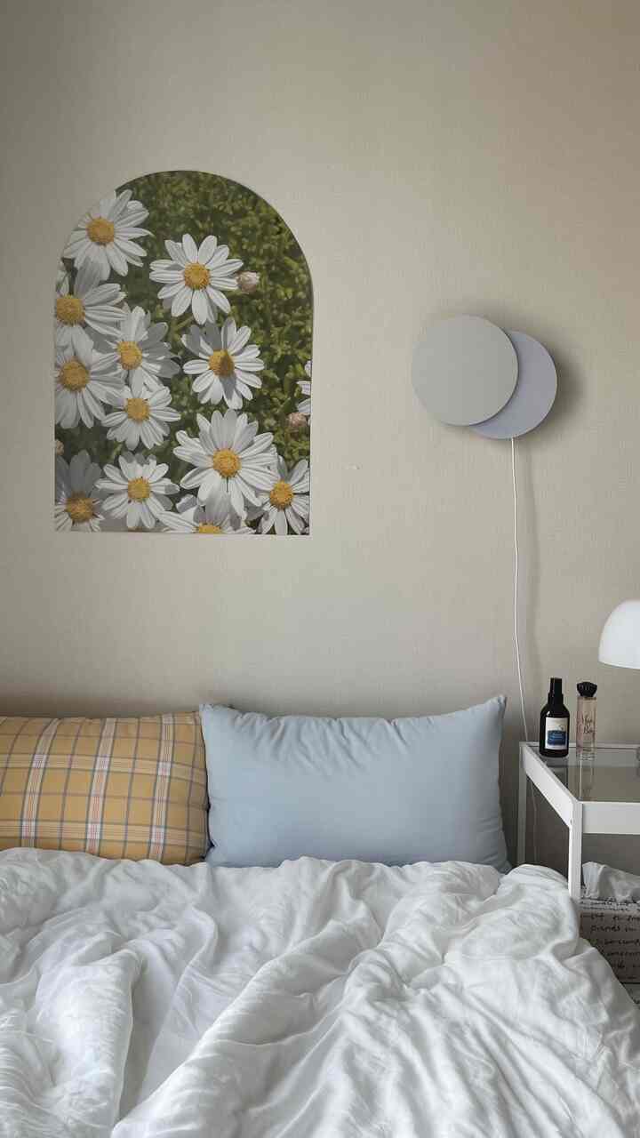 White and yellow toned studio bedroom featuring a daisy poster, simple cushions, and clean duvet cover with a spring vibe