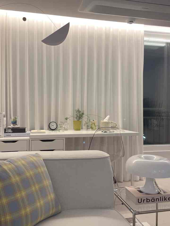 明るく整った白色のリビング、シンプルモダンなデザインと透明な椅子が置かれたホームオフィス空間