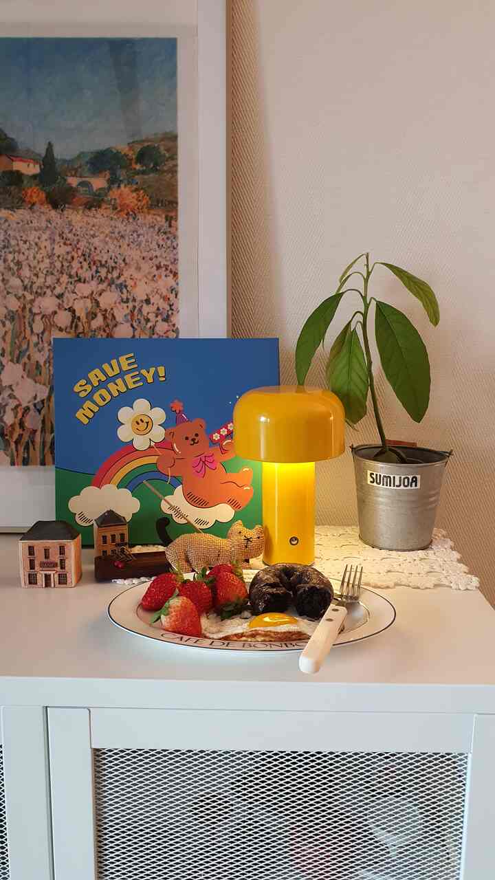 A clean living room cabinet in white and yellow tones featuring home cafe items and an avocado plant