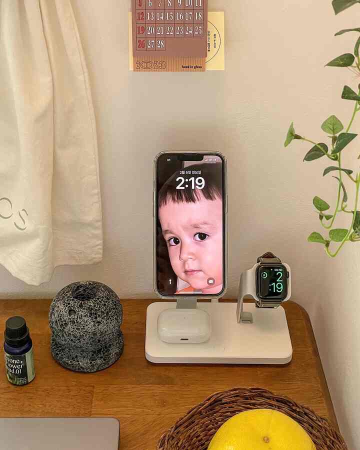 Natural tone desk featuring smartphone docking station, volcanic stone diffuser, and citrus fruit creating cozy home office setting