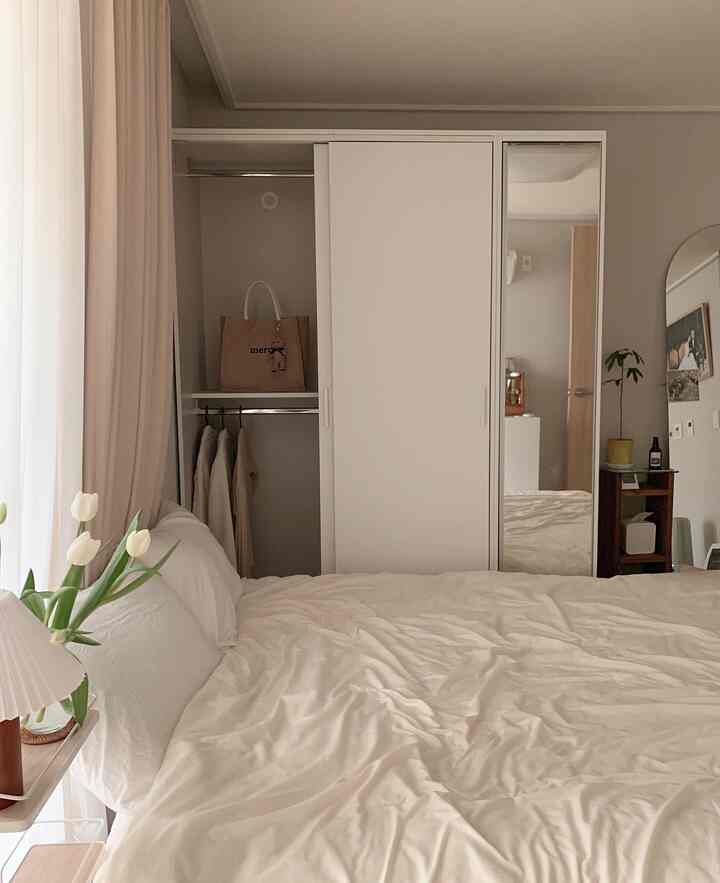 白とナチュラルカラーの寝室、スライディングクローゼットと快適なベッドが配置されたシンプルモダンなインテリア