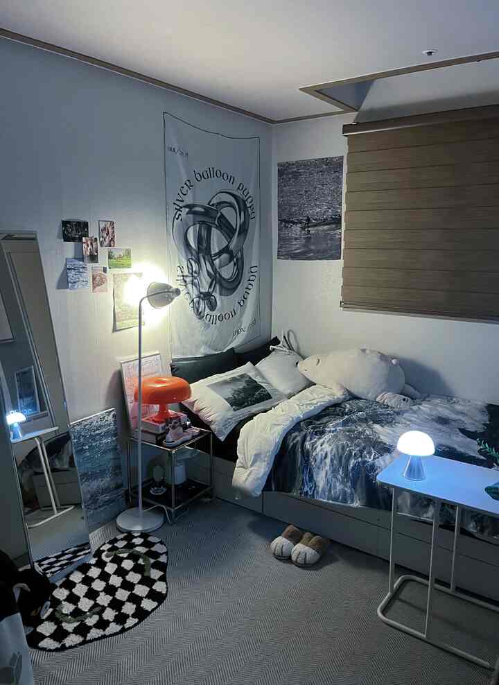 清潔感のあるホワイトとグレーの寝室、ベッドやポスター、多様な照明が調和した雰囲気のあるインテリア