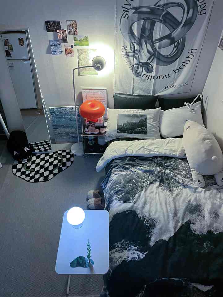 白と黒の調和が美しい一人暮らし用の狭い寝室、ベッドとナイトテーブル、フロアランプが配された落ち着いた空間