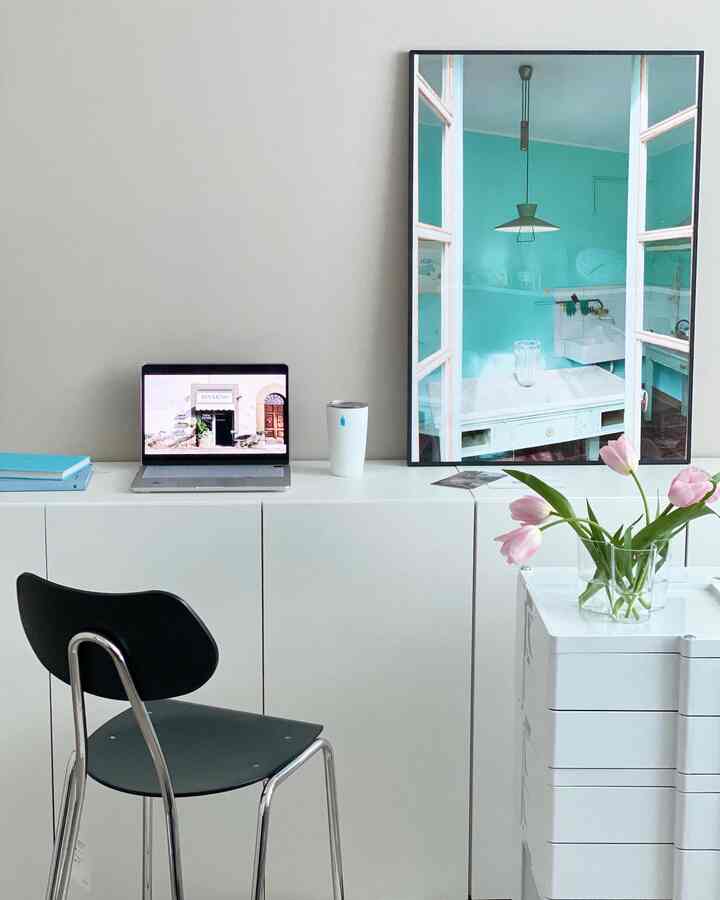 Minimal home office space in white and mint tones featuring clean layout and a large poster that defines the atmosphere