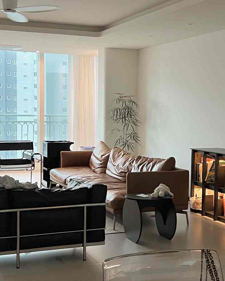 White toned living room featuring a brown leather sofa and black armchair with a cozy atmosphere