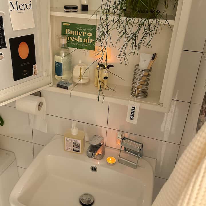 白いタイル壁のナチュラルなバスルーム、植物とバスルーム用品が配置され、赤ちゃんと暮らす空間を感じさせるインテリア