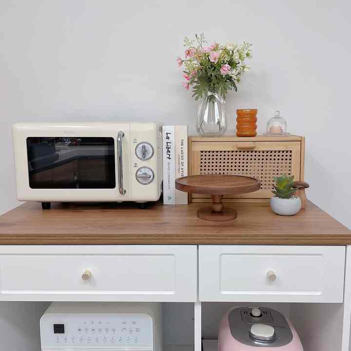 白と木目調の調和がとれたキッチン、電子レンジとラタン収納が配置された雰囲気のあるインテリア