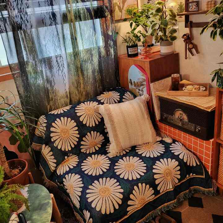 Wood tone and white living room featuring floral patterned sofa, cushion, and various plants creating a cozy atmosphere