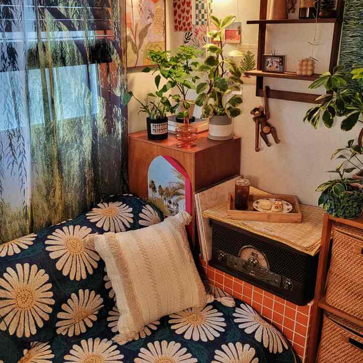 Cozy living room with natural wood tones and blue floral sofa, decorated with lush plants and vintage objects