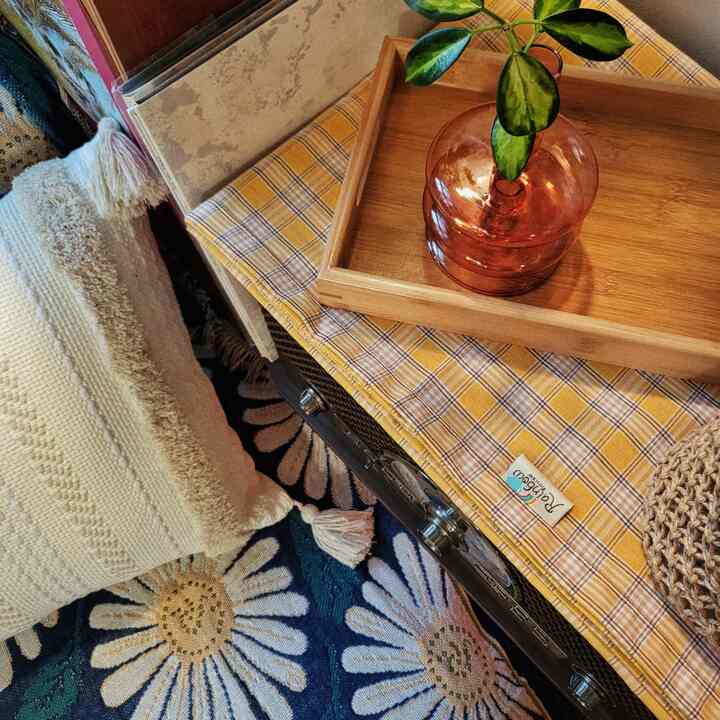 Natural space featuring yellow check tablecloth and wood tone tray, with cozy throw blankets and textured cushions