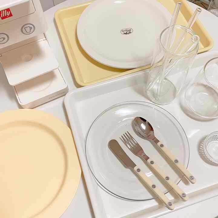 白と黄色のトーンのホームカフェ空間、イリーのコーヒーマシンとカトラリー、皿、グラスが整然と配置されたミニマルなインテリア