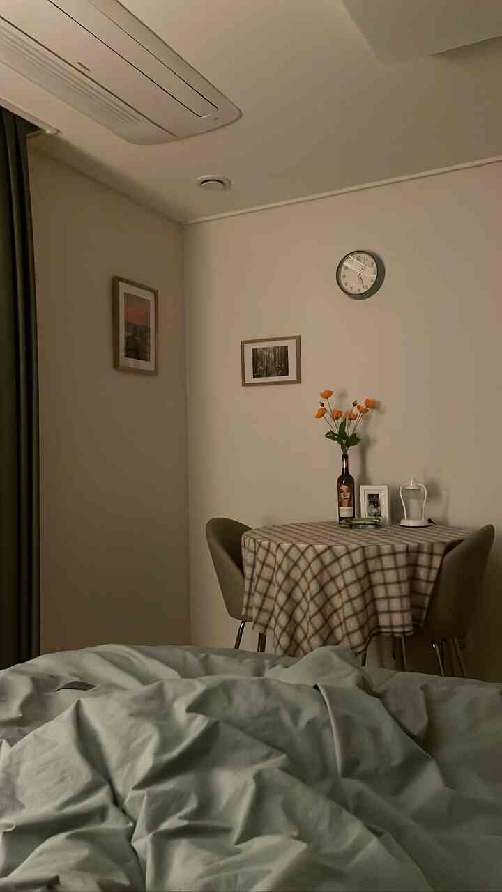 ベージュとライトグレーのトーンの寝室、チェック柄のテーブルと額縁が配置された居心地の良い空間