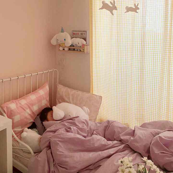 Soft pink and yellow toned kids' room with white metal bed frame and cozy purple duvet cover creating a warm atmosphere