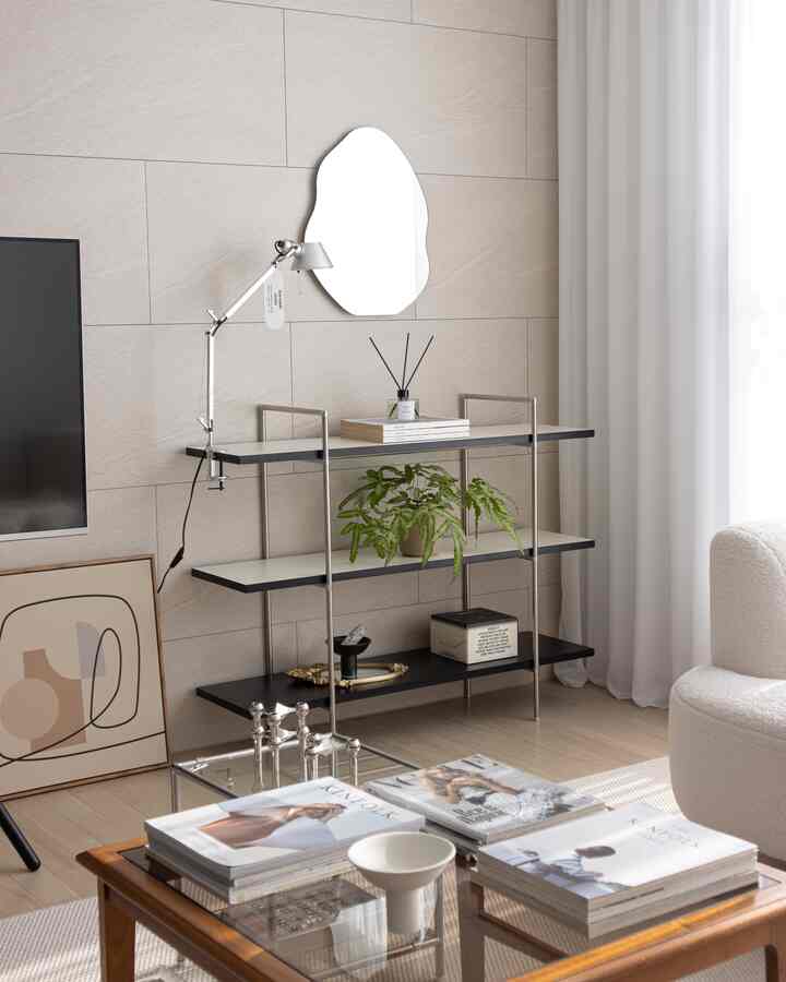 ベージュとホワイトの色調のリビング、中心に不規則形状の壁掛け鏡と棚、自然な木目調家具が配置された雰囲気のあるインテリア