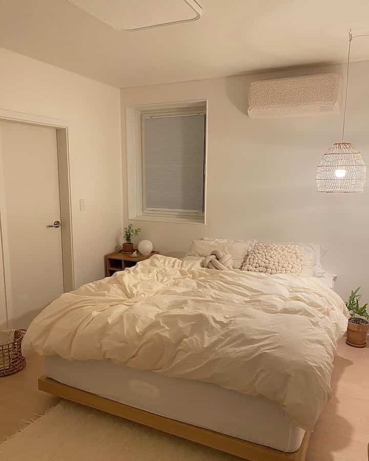 White and natural tone bedroom featuring rattan pendant light and cozy bedding with a warm, inviting atmosphere