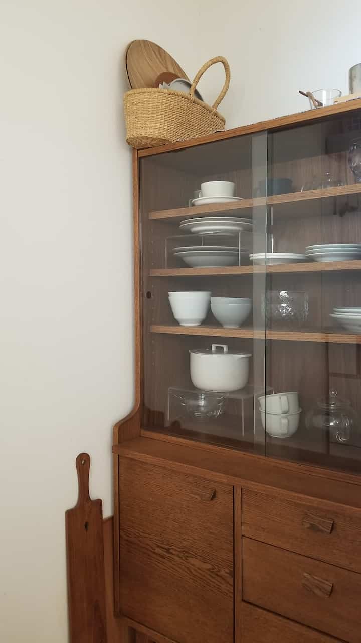 A natural wood-tone kitchen cabinet neatly organized with dishware creating a clean and simple space