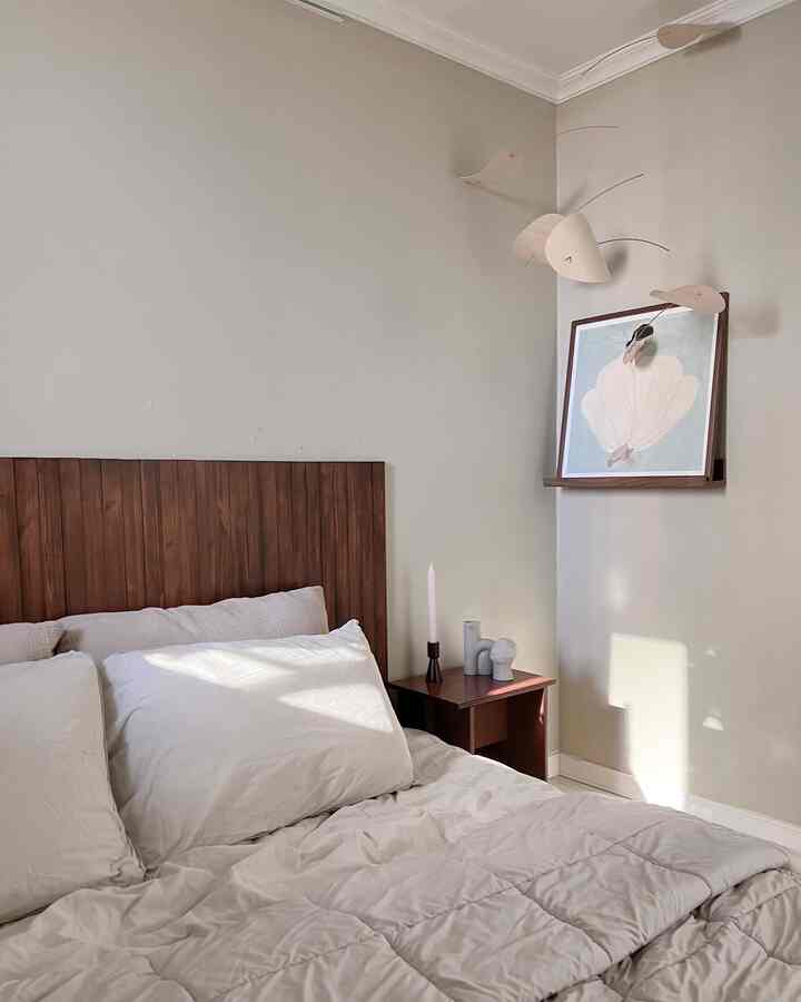 Natural beige-toned bedroom featuring wooden bed and nightstand with a simple and calm atmosphere